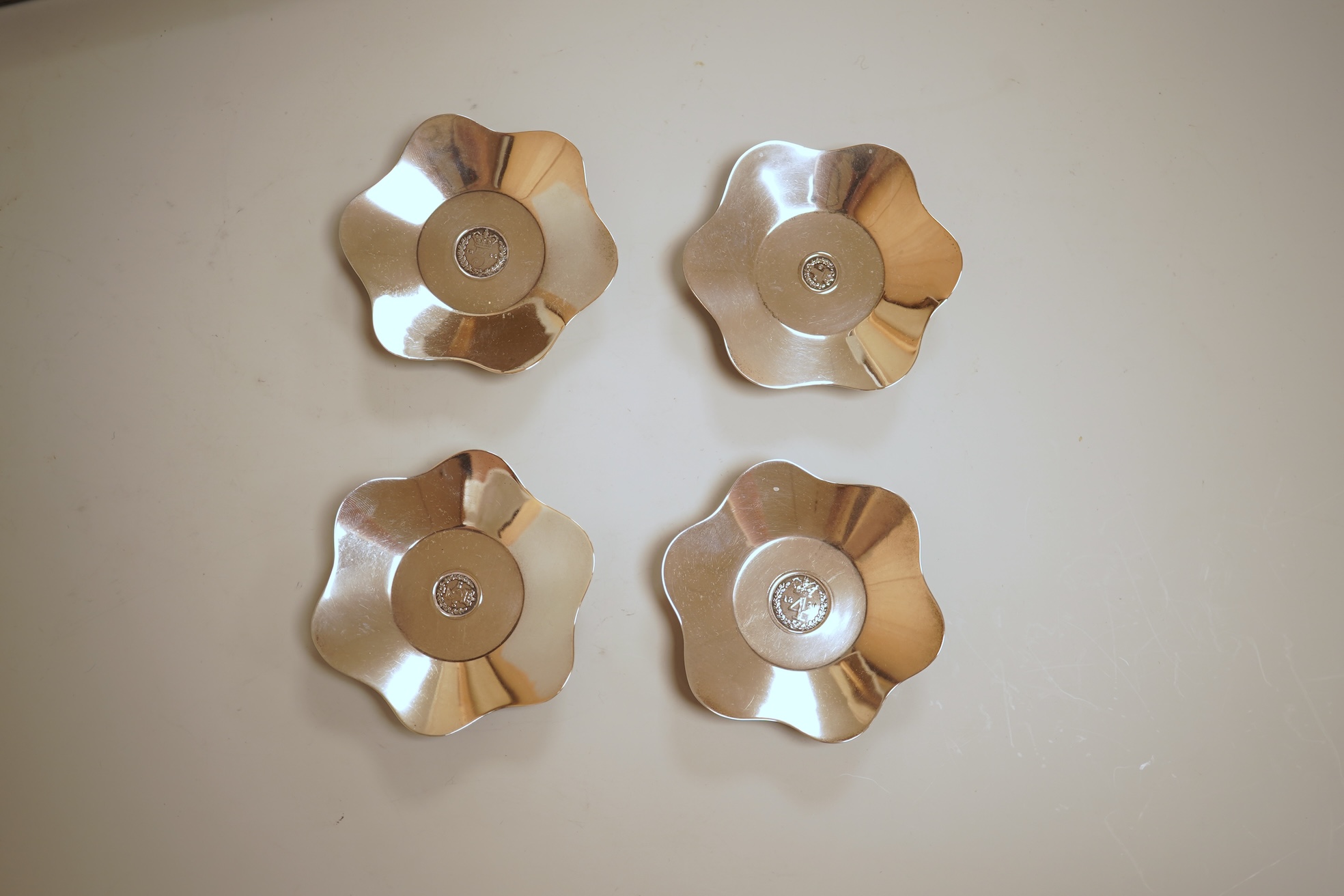 A cased set of four George V silver flower head shaped nut dishes, each inset with an 1850 maundy coin, Walker & Hall, Birmingham, 1936, diameter 77mm.